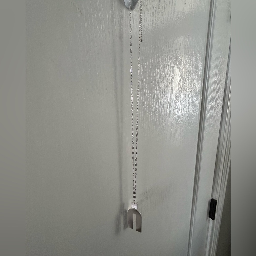 Silver necklace with rainbow shape at bottom